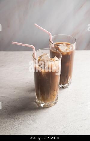 Cold coffee with milk and ice in tall glasses with tubes on a light background. Stock Photo