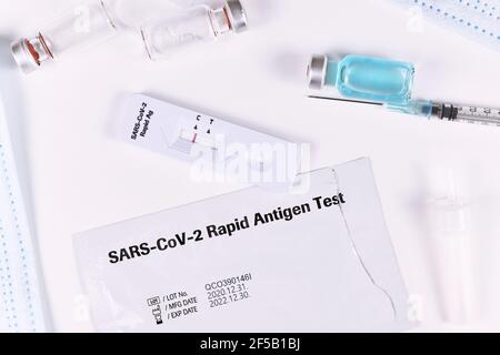 Tools to fight Corona Virus pandemic including rapid antigen test and vaccine vials with syringe Stock Photo