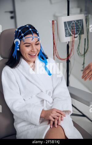 High-spirited female patient sitting in the chair before the electroencephalography Stock Photo