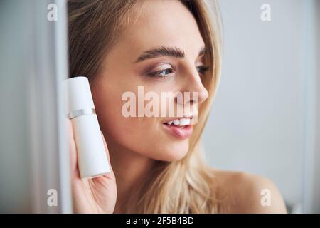 Pleased blonde female showing her body lotion Stock Photo