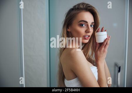 Attractive long-haired woman showing her beauty product Stock Photo