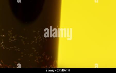 Small bubbles in dark fizzy drink, closeup detail with yellow background Stock Photo