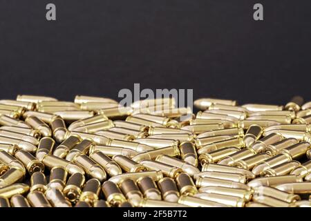 Many brass gun bullets on black table closeup view, space for text upper side Stock Photo