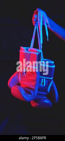 Beautiful female boxer training, red boxing gloves, ring with red and blue lights, industrial gym, neon lights. selective focus Stock Photo