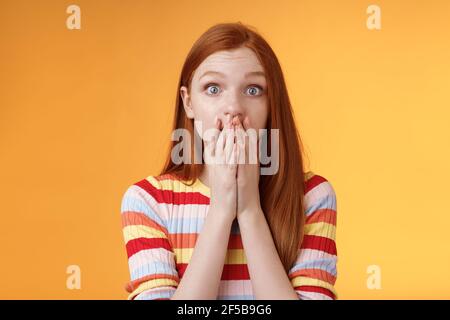 Shocked speechless impressed sensitive redhead european girl reacting stunning rumor gossiping find out secret gasping cover mouth palm stare camera Stock Photo
