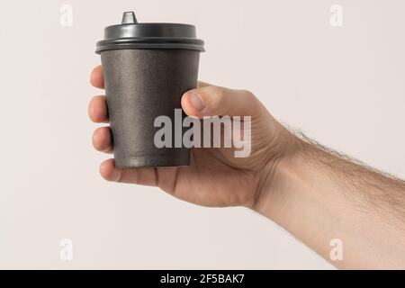 A paper cup of coffee in the hand. White paper cup of coffee in hand. For mock up. Isolated. On colored background Stock Photo