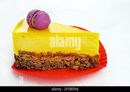 Yellow slice of cake with pasta. Cheesecake with mango on shortcrust pastry. Delicious bright dessert on a white plate. Lemon souffle Stock Photo