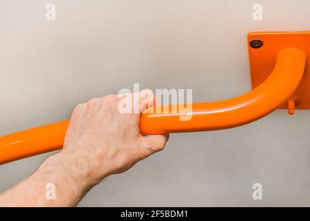 Man's hand holding a metal handrail in the toilet. Stock Photo