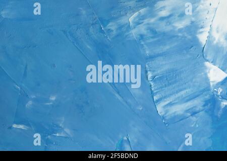 The surface is covered with blue paint with white streaks background. texture of paint on canvas. Color putty on the wall close-up. Stock Photo