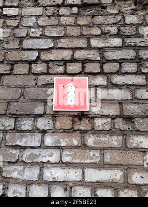 Fire extinguisher sign on a brick wall with bullet holes close-up. Stock Photo