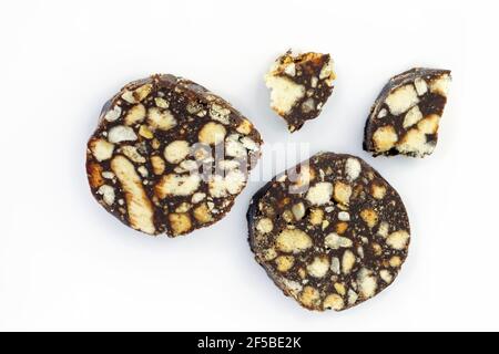 Chocolate biscuits with pieces of nuts and white biscuits. Homemade chocolate sausage cookies on a white plate top view. Cake based on butter, nuts an Stock Photo