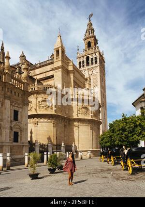 Woman posing with the Giralda and the Cathedral of Saint Mary, Seville, Spain Stock Photo