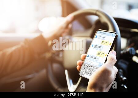 Man Typing Text Message On Mobile Phone While Driving Car Stock Photo