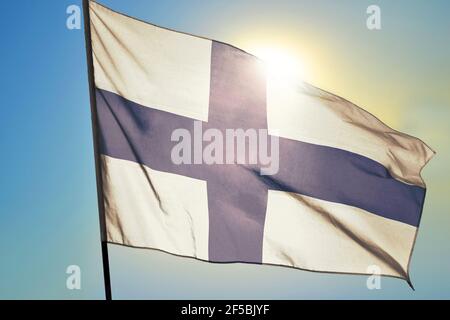 Finland flag waving on the wind in front of sun Stock Photo