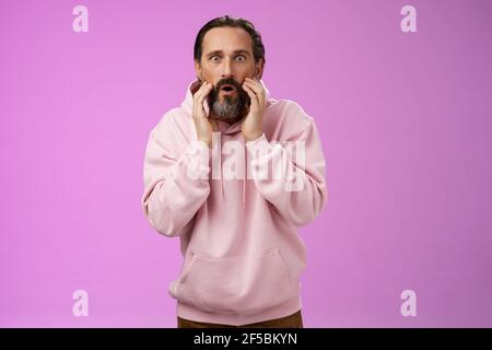 Impressed surprised handsome adult bearded man grey hair attend barber shop cannot believe see own reflection become stylish cool-looking touching Stock Photo