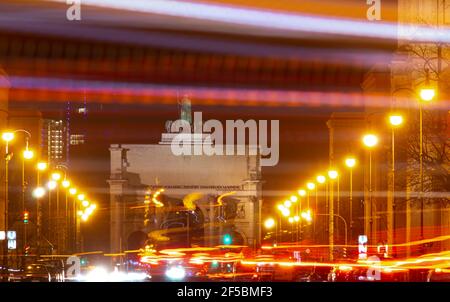 Munich, Germany. 25th Mar, 2021. The lights of the cars draw their stripes on a long exposure showing Ludwigstrasse and the Siegestor, en 19th century triumphal arch crowned by a bronze Bavaria with lion quadriga. Credit: Peter Kneffel/dpa/Alamy Live News Stock Photo