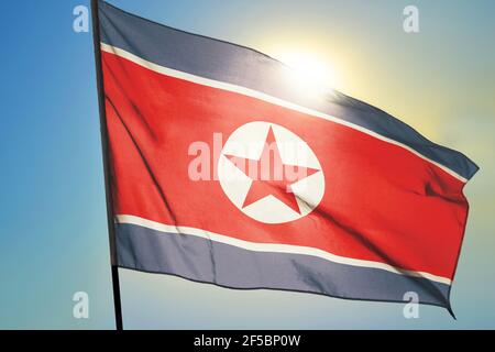 North Korea flag waving on the wind in front of sun Stock Photo