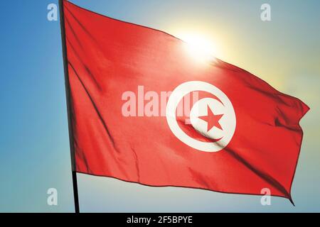 Tunisia flag waving on the wind in front of sun Stock Photo