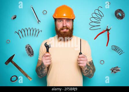 Confused man with screwdriver and spanners. worried and uncertain expression. cyan background Stock Photo