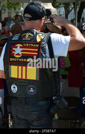 Rear view of saluting Veteran wearing a vest with multiple badges with Vietnam Brotherhood messages, a right wing organization, in Sarasota, FL, USA Stock Photo