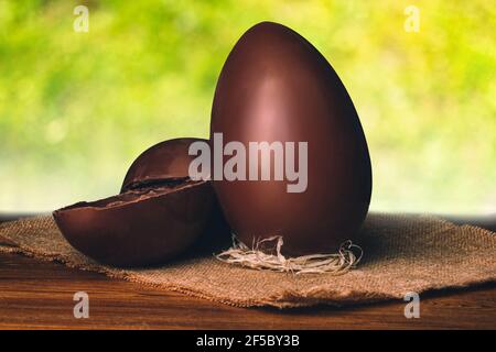 Chocolate Easter eggs and blurred green nature background. Natural template with beauty bokeh and warm sunlight. Concept banner for products display Stock Photo