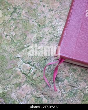 Red brown leather cover book with bookmark ribbon. On top of stone surface. Flat lay view. Stock Photo