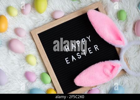 Stylish background with bunny ears and text Happy Easter on white fur background. Flat lay, top view, mockup, overhead, template Stock Photo