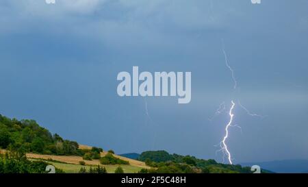 Storm with lightning over the hilly landscape Stock Photo