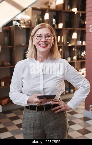 Portrait of successful elegant businesswoman smiling at camera while using digital tablet in the restaurant Stock Photo