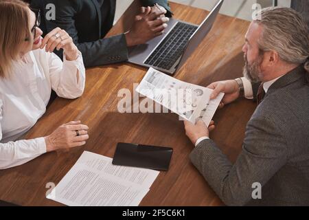 Group of business people sitting at the table and discussing documents together in team during meeting at office Stock Photo
