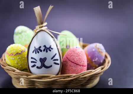 Happy easter bunny egg and eggs colored eggs  in a basket isolated on a trendy black background. Minimal easter concept. Easter card with copy space f Stock Photo