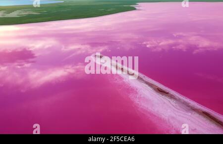Aerial view of a pink lake and an elongated island of salt and sand. Therapeutic salt lakes with healing properties. Stock Photo