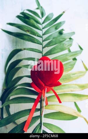 conceptual image of romantic tropical holidays for couples with plam leaf and two red velvet hearts Stock Photo