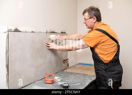 The tiler is installing the tiles on the kitchen wall. Stock Photo