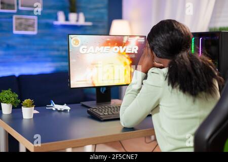 Disappointed sad african woman after losing online game competition Angry professional gamer gaming over during an space shooter online video game. Stock Photo