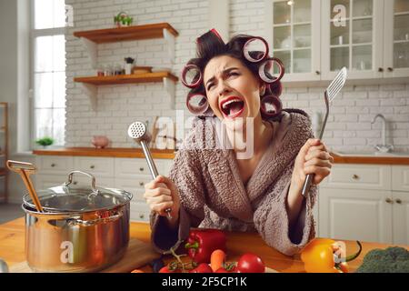 Unhappy young housewife sick and tired of cooking and housework crying in the kitchen Stock Photo