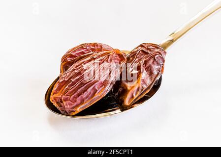 Close-up of dates on a silver spoon on a white tablecloth, London, UK Stock Photo