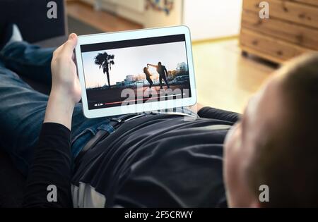 Watching VOD service and online movie stream. On demand film streaming, tv series or music video in smart device screen. Man enjoying entertainment. Stock Photo