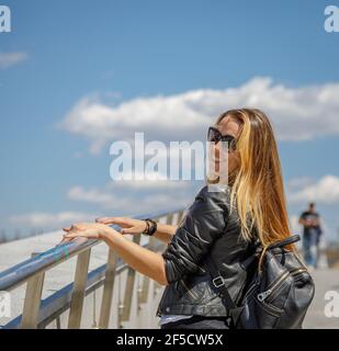 A beautiful young girl in sunglasses walks around the city. Long blonde hair flutters in the wind. Moscow Russia June 20, 2018 Stock Photo