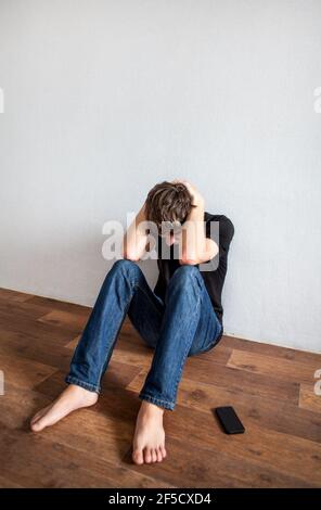 Sad Young Man on the Floor in the Room Stock Photo