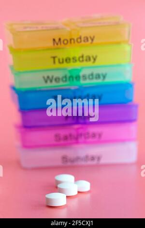 Pill box reminder, hand taking medicine daily pills in colorful box on pink background, elderly,senior,business,health,medication concept modern Stock Photo
