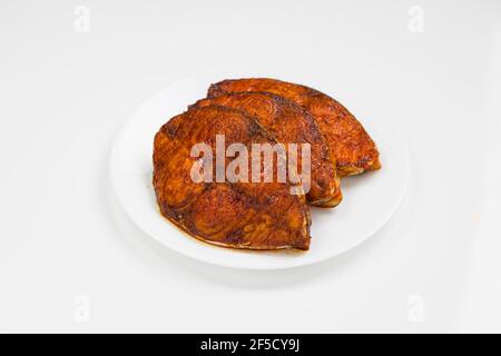 Seer fish fry arranged beautifully on awhite ceramic plate with white textured background,isolated. Stock Photo