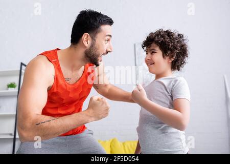 Cheerful muslim man in sportswear looking at son at home Stock Photo