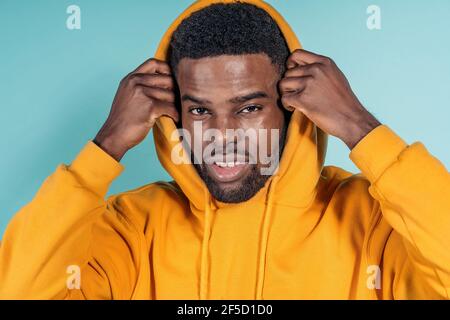 Stock photo of expressive black boy wearing hoodie posing in studio shot against blue background. Stock Photo