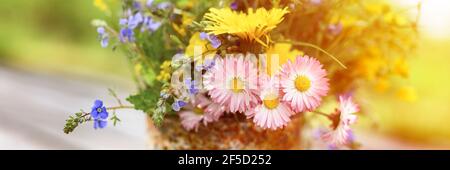 a bouquet of wildflowers of forget-me-nots, daisies and yellow dandelions in full bloom in a rusty rustic jar against a background of wooden planks in Stock Photo