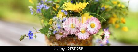 a bouquet of wildflowers of forget-me-nots, daisies and yellow dandelions in full bloom in a rusty rustic jar against a background of wooden planks in Stock Photo