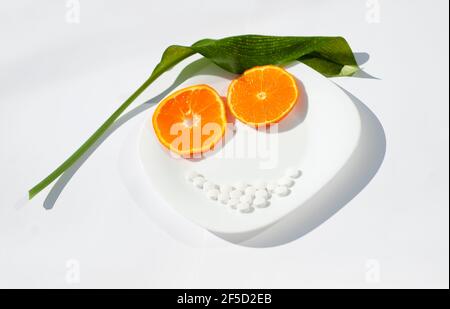 Orange slices are two eyes. The white pills are the mouth. The green leaf is the hair. The plate is this face. Healthy food and supplements theme. Stock Photo