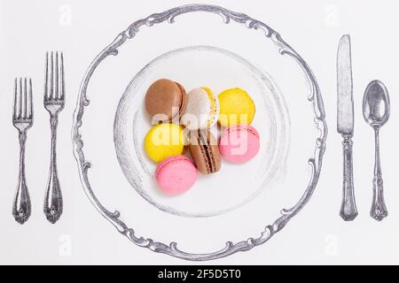 Macarons served on a plate next to a tall and small fork Stock Photo