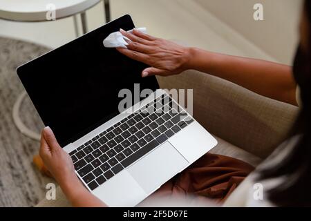 Midsection of mixed race businesswoman sitting disinfecting laptop computer Stock Photo