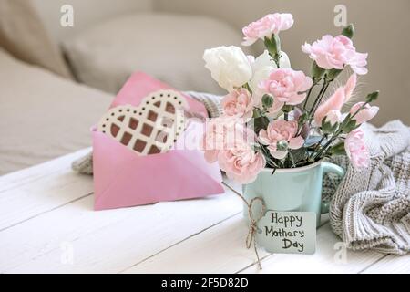 A festive composition with fresh flowers in a vase, decorative elements and a wish for Happy Easter on a postcard. Stock Photo